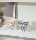Handmade ceramic mugs with bow handles in pink and blue, perfect for coffee or tea